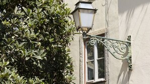 Un edificio con varias ventanas, un farol y un árbol en la calle.
