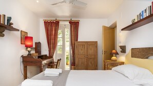 Una habitación de hotel con una cama, un escritorio, una silla, una estantería y un armario.