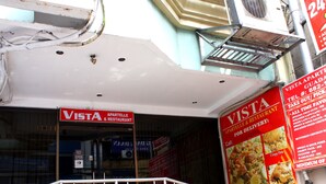 A storefront with a sign reading "VISTA APARTELLE & RESTAURANT" and a menu board advertising various dishes. - Vista Apartelle & Restaurant (Makati)
