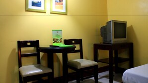 A room with two wooden chairs, a small table with a green menu, and a television on a wooden stand. - Vista Apartelle & Restaurant (Makati)