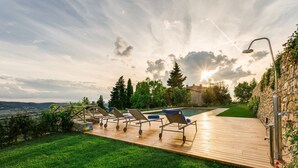 A poolside area with lounge chairs, a wooden deck, and a stone wall. - Luxury Chianti For Four in Panzano Chianti (Panzano)