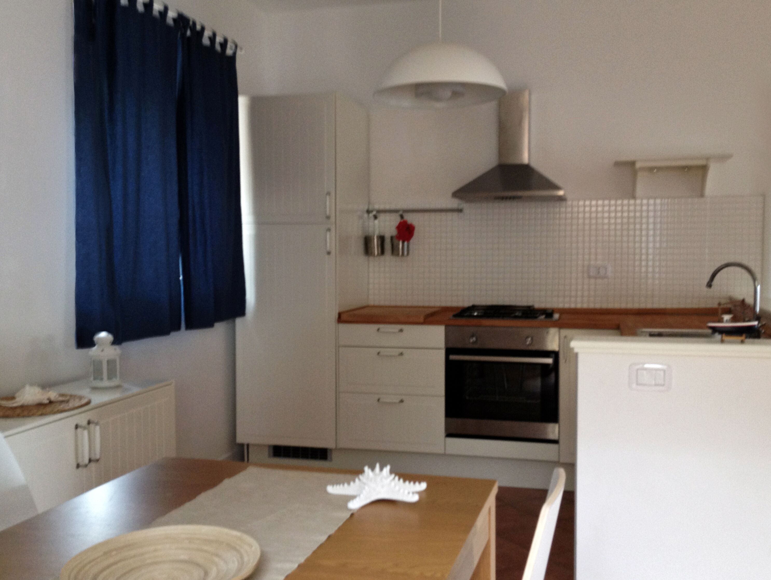 Una cocina moderna con armarios blancos, encimera de madera, estufa y pileta.
