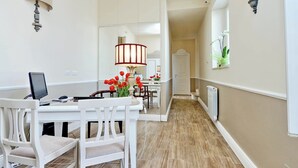 Un coin repas avec une table blanche, des chaises et une lampe.