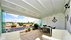 Un balcon avec un canapé blanc, une table à manger et des plantes en pot.