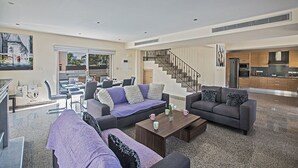 A spacious living room with a sofa set, a coffee table, and a staircase leading to the upper floor. - Protaras Villa Theodora 1 - CHG (Paralimni)