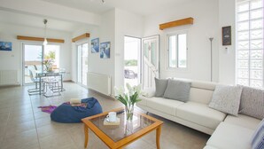 A spacious living area with a sofa, coffee table, and a dining table with chairs.