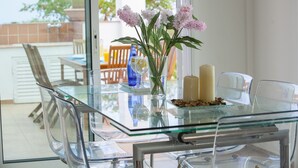 A glass-top dining table with a vase of flowers, candles, and a glass of water.