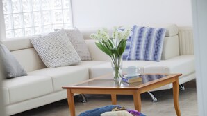 A living room with a sofa, a coffee table, a vase with flowers, and a book on the floor.