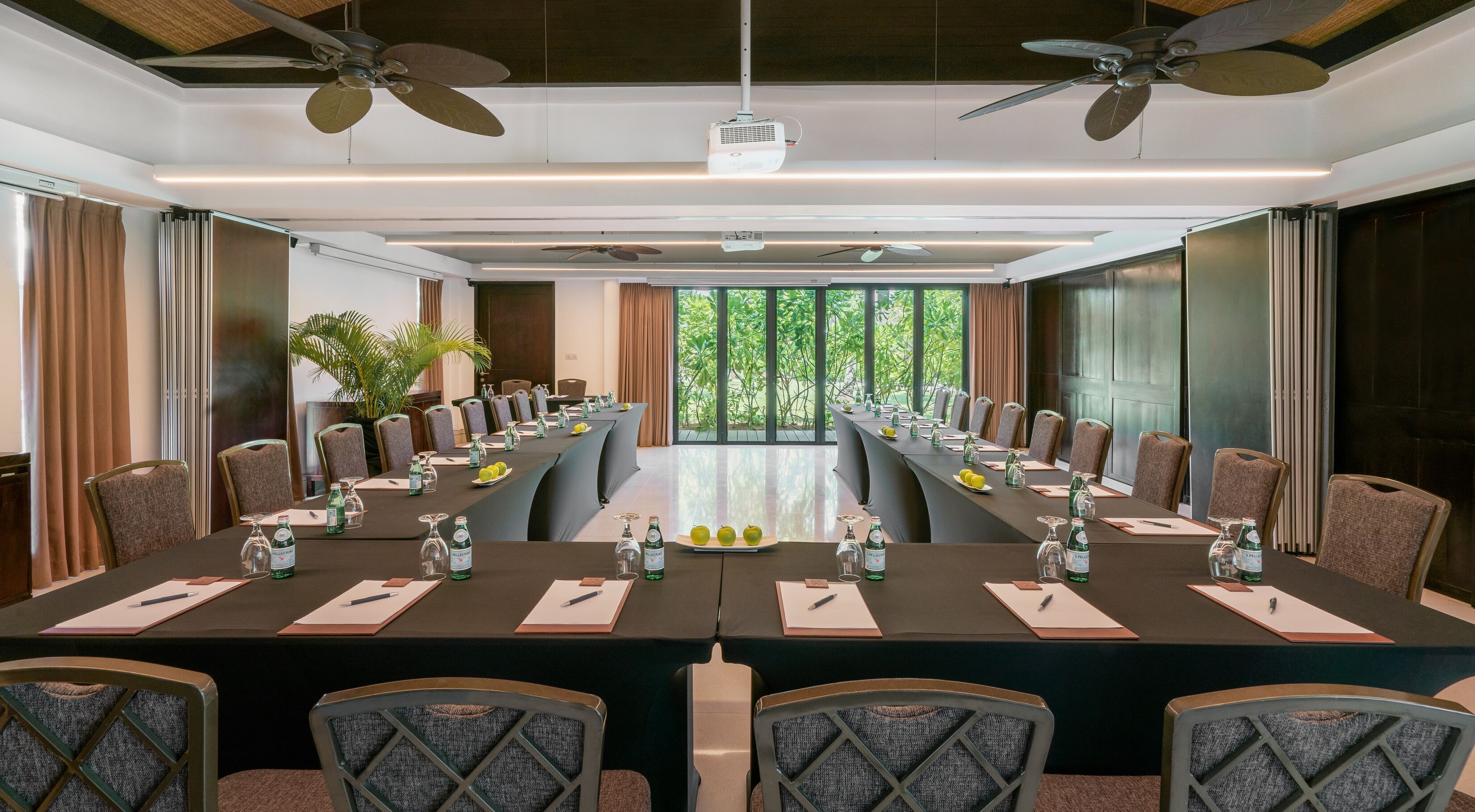 A conference room with a long table, chairs, ceiling fans, and large windows.