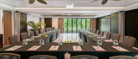 A conference room with a long table, chairs, ceiling fans, and large windows.