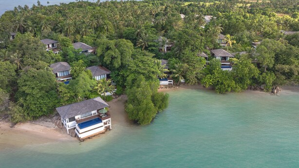 An aerial view of a tropical island with several houses surrounded by dense vegetation and a clear turquoise sea. - The Residence Bintan (Bintan)