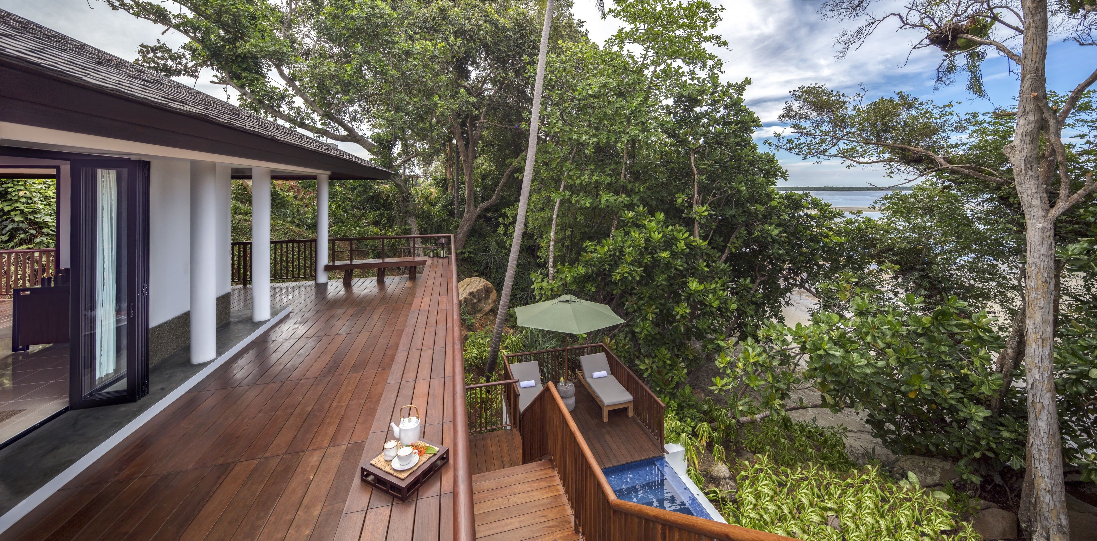 A wooden deck with a hot tub, lounge chairs, and a table set with tea and snacks.
