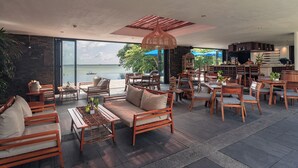A spacious outdoor seating area with wooden furniture and a view of the sea. - The Residence Bintan (Bintan)