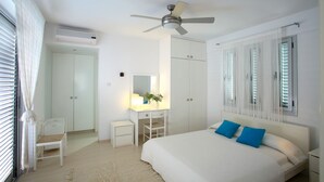 Un dormitorio con cama, escritorio, silla, armario y ventilador de techo.