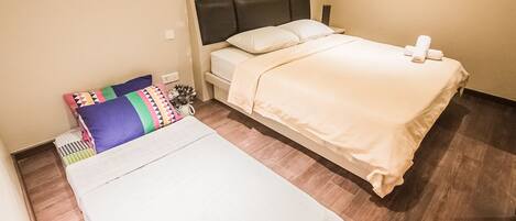 A hotel room with a single bed, a smaller bed, and a nightstand.