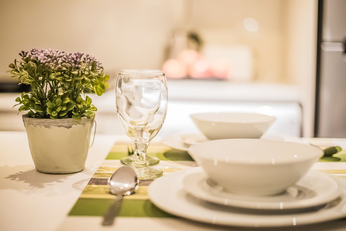 A dining table with a white bowl, a glass, and a potted plant.