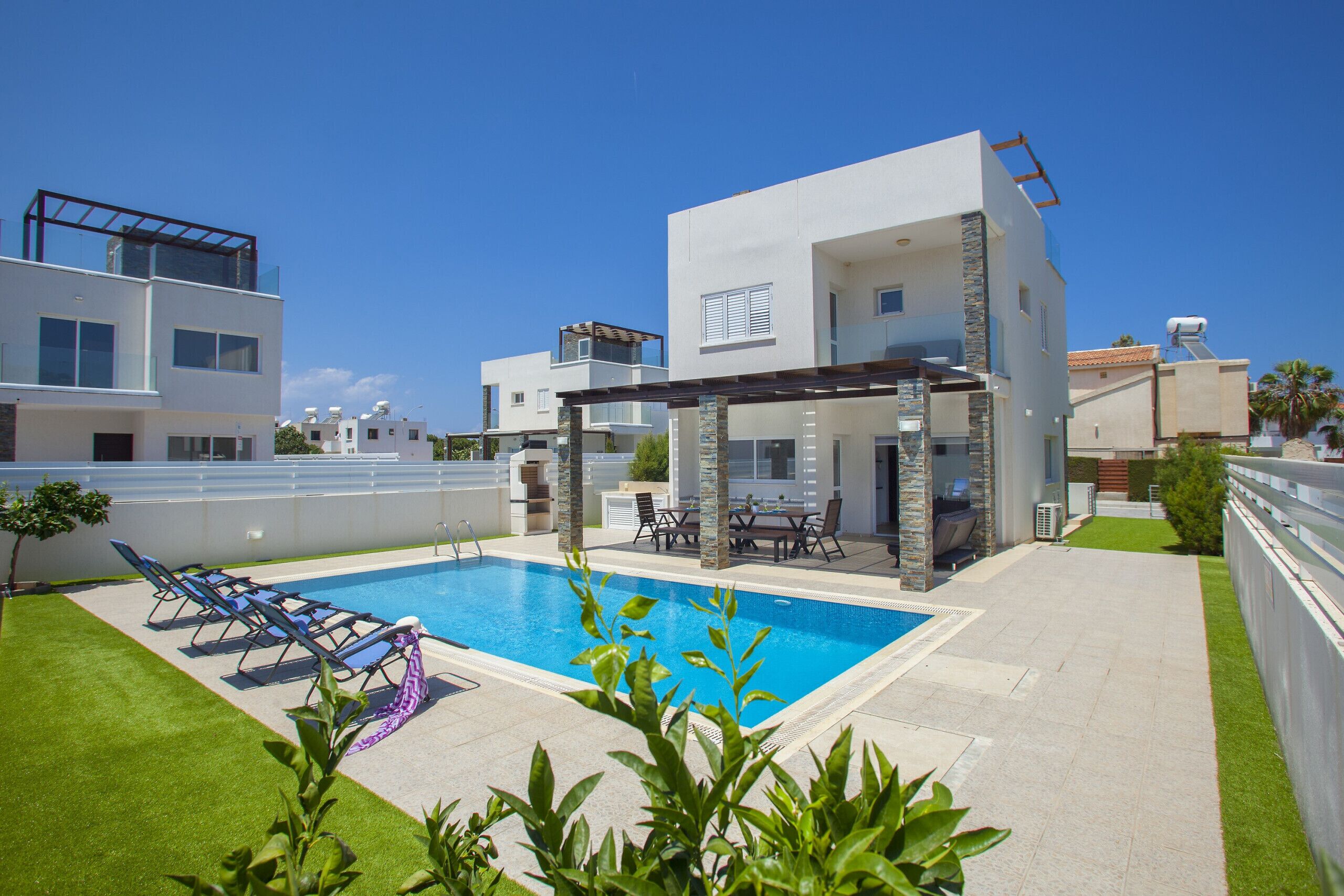 A modern two-story house with a swimming pool, outdoor seating, and a pergola.