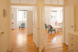 A spacious room with wooden flooring, white walls, and a dining area with colorful chairs. - Bright and Spacious Apartment in historic Lisbon neighborhood - TTL269 (Lisboa ciudad)