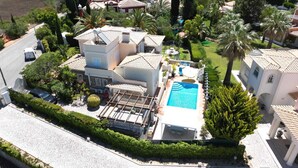 Ein Wohnhaus mit Swimmingpool, überdachter Terrasse und gepflegtem Garten.