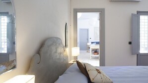 Une chambre à coucher avec un lit, une table de chevet, une lampe et une porte donnant sur une autre pièce.