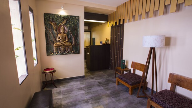 Ett entrérum med en Buddha-staty, en receptionsdisk, en bänk och en golvlampa.
