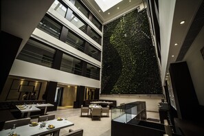 A modern interior with a dining area, a high ceiling, and a vertical garden wall. - Hash Six Hotels (Coimbatore)