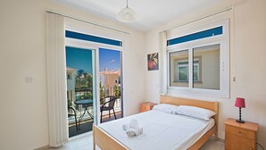 Une chambre à coucher avec un lit, une table de chevet, une lampe et une vue sur l’extérieur.