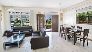 Un salon moderne comprenant un canapé, une table basse en verre et un coin repas avec une table et des chaises.