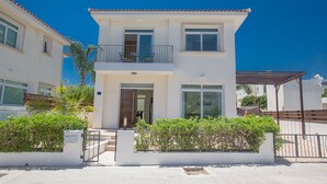 Un immeuble résidentiel de deux étages doté d’un balcon, d’une porte d’entrée et d’un petit jardin.