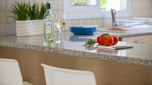 A kitchen counter with a bottle of white wine, a glass, and fresh tomatoes. - Protaras Villa Posidonas 3 Near The Beach (Protaras)