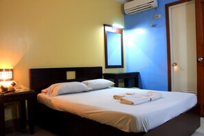 Ein Hotelzimmer mit Bett, Nachttisch und Spiegel an der Wand.