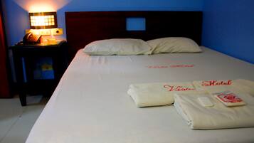 A hotel room with a neatly made bed, a bedside table with a lamp, and a telephone.