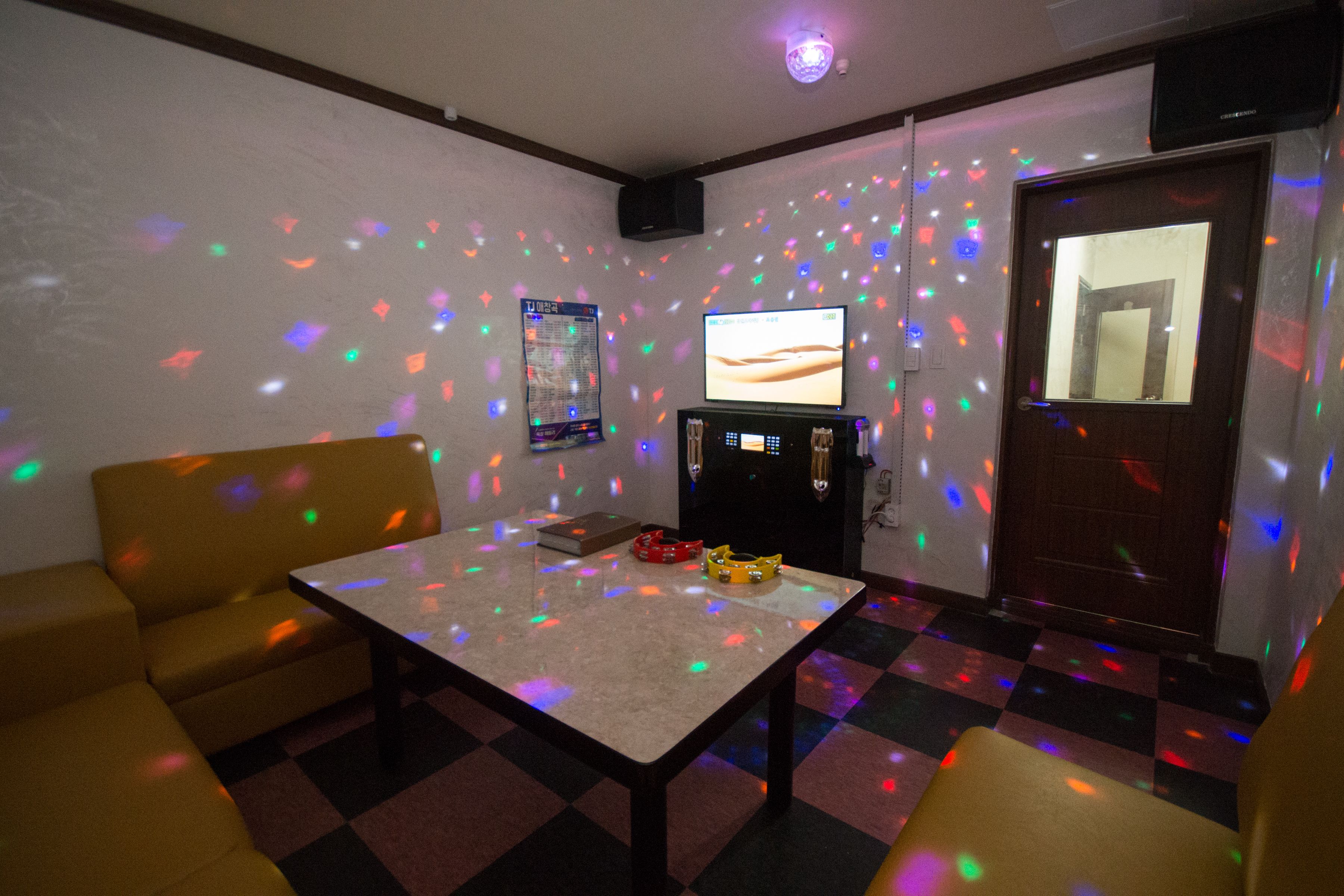 A room with a checkered floor, a television, a table, and two sofas.