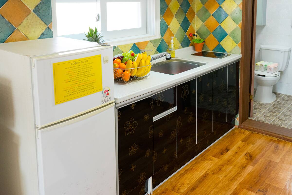 A kitchen with a refrigerator, sink, and wooden cabinets.