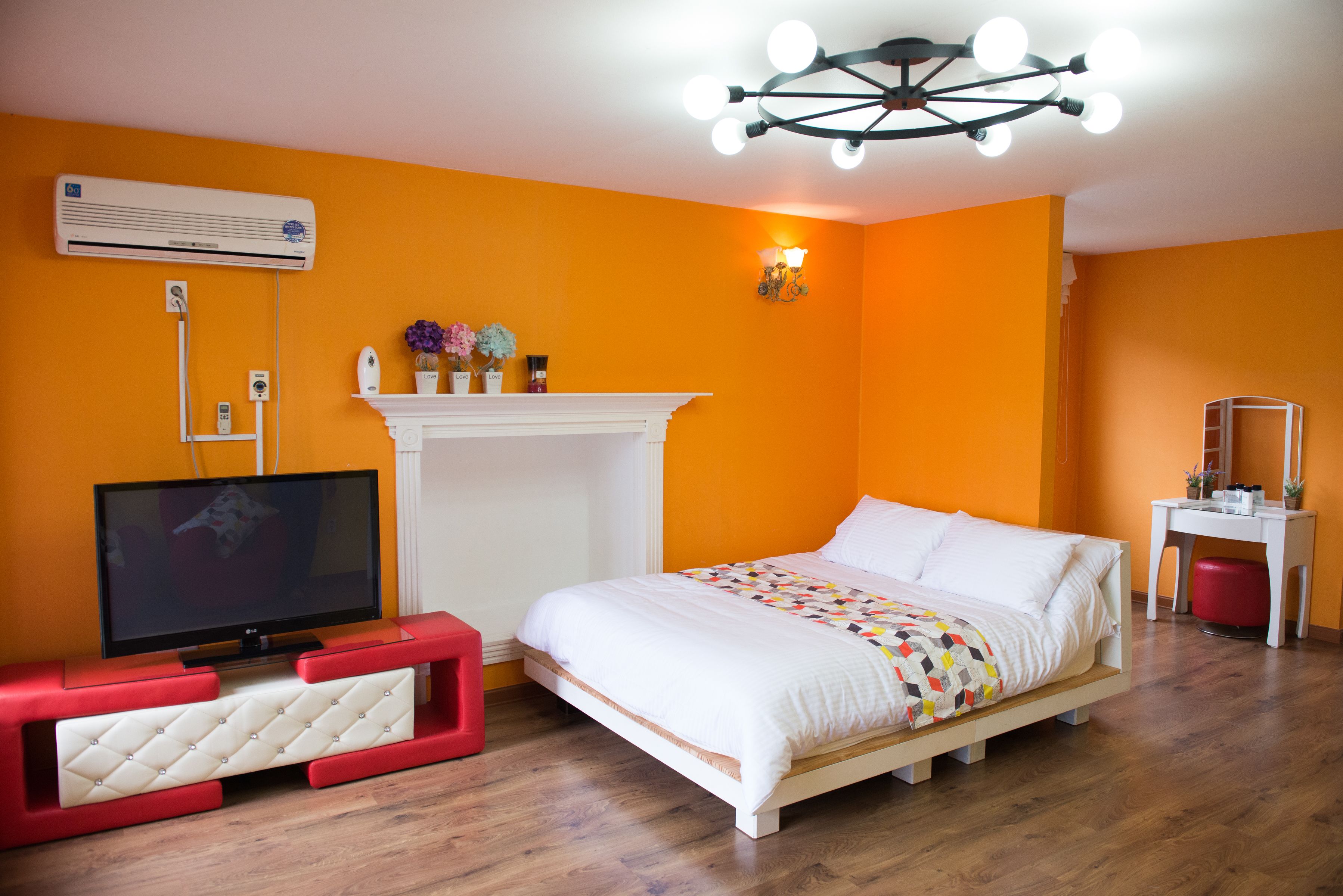A bedroom with a bed, a TV, a fireplace, and an air conditioning unit.