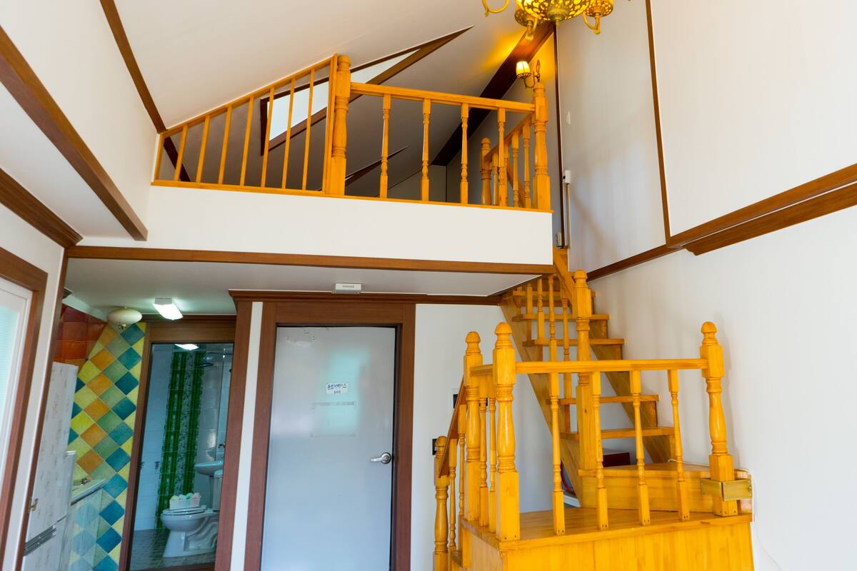 A multi-level wooden staircase with a handrail, a door with a sign, and a tiled wall with a diamond pattern.