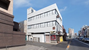 A modern building with a flat facade, large windows, and a visible storefront on the ground floor. - COCOSHUKU Tokyo Nakano (Tokyo)