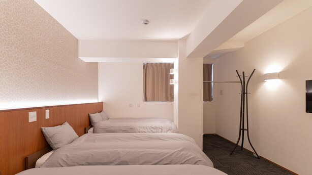 A hotel room with two beds, a coat rack, a window with curtains, and a wall-mounted light fixture. - COCOSHUKU Tokyo Nakano (Tokyo)