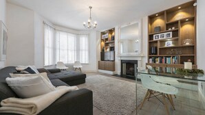 Una sala de estar moderna con un sofá, una mesa de centro de vidrio y una chimenea.