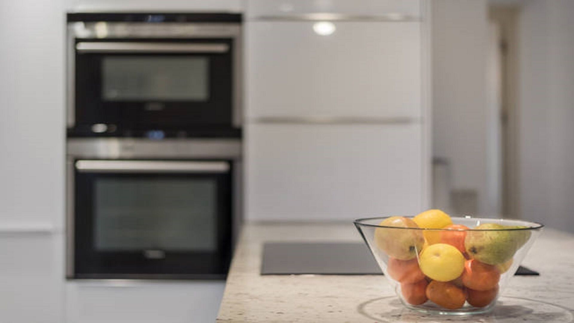 Een keuken met een glazen schaal met fruit op een aanrecht.