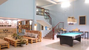 A spacious indoor area with a pool table, wooden furniture, and a staircase leading to an upper level. - Ha Giang Amazing Hostel (Ha Giang 2)