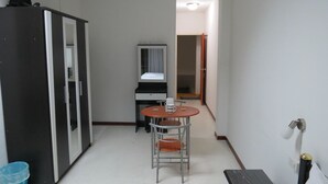 Una habitación pequeña y funcional con escritorio, silla, armario y espejo.