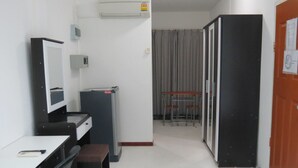 Una habitación pequeña con escritorio, silla y una kitchenette.