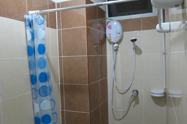 Zona de ducha con cabezal de ducha de mano, panel de control en la pared y cortina con lunares azules.