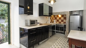 A compact kitchen with a microwave, stove, and refrigerator. There is a window with a view of greenery outside.