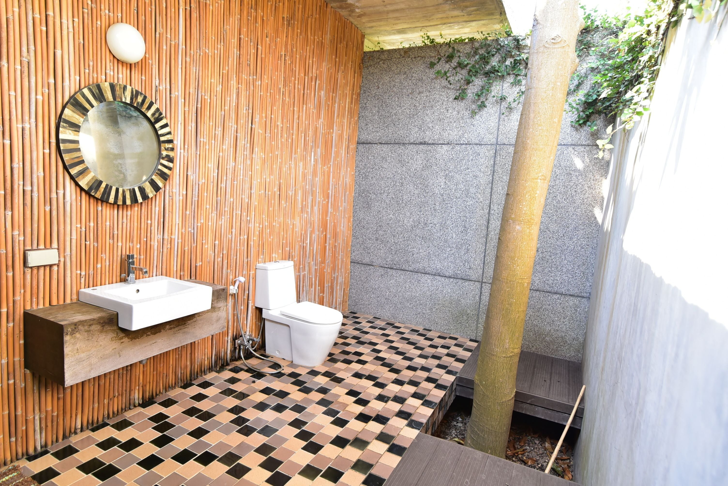 A bathroom with a wooden wall, a sink, a toilet, and a mirror.