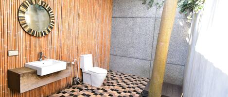 A bathroom with a wooden wall, a sink, a toilet, and a mirror.