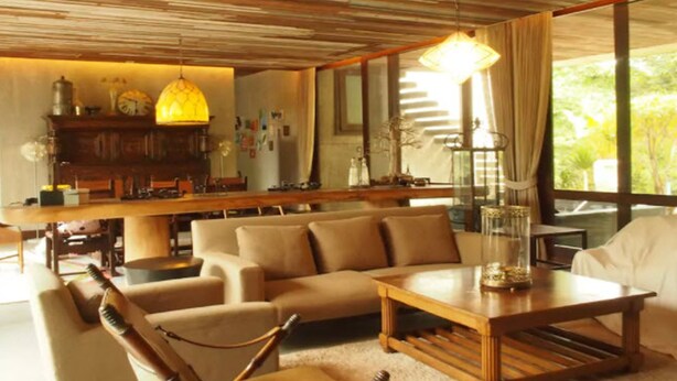 A cozy living room with a sofa, coffee table, and a wooden ceiling. - Uncle Jo Ranch (Pak Chong)