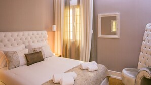 Un lit bien fait, avec des oreillers et une serviette pliée, une chaise et un miroir au mur.