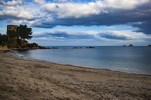 Une plage avec une formation rocheuse et un ciel dégagé.